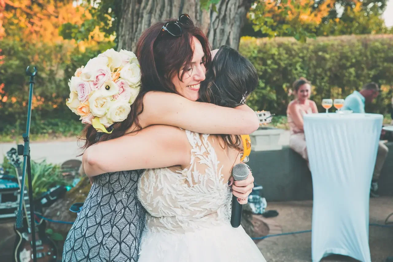 Une mariée et Laure partagent une étreinte lors d’un mariage en extérieur